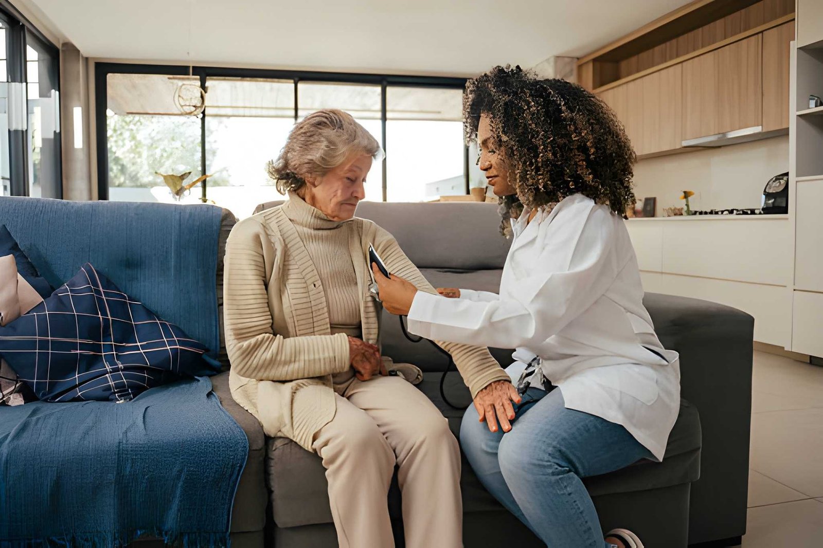 Caregiver checking in with an older adult on a sofa